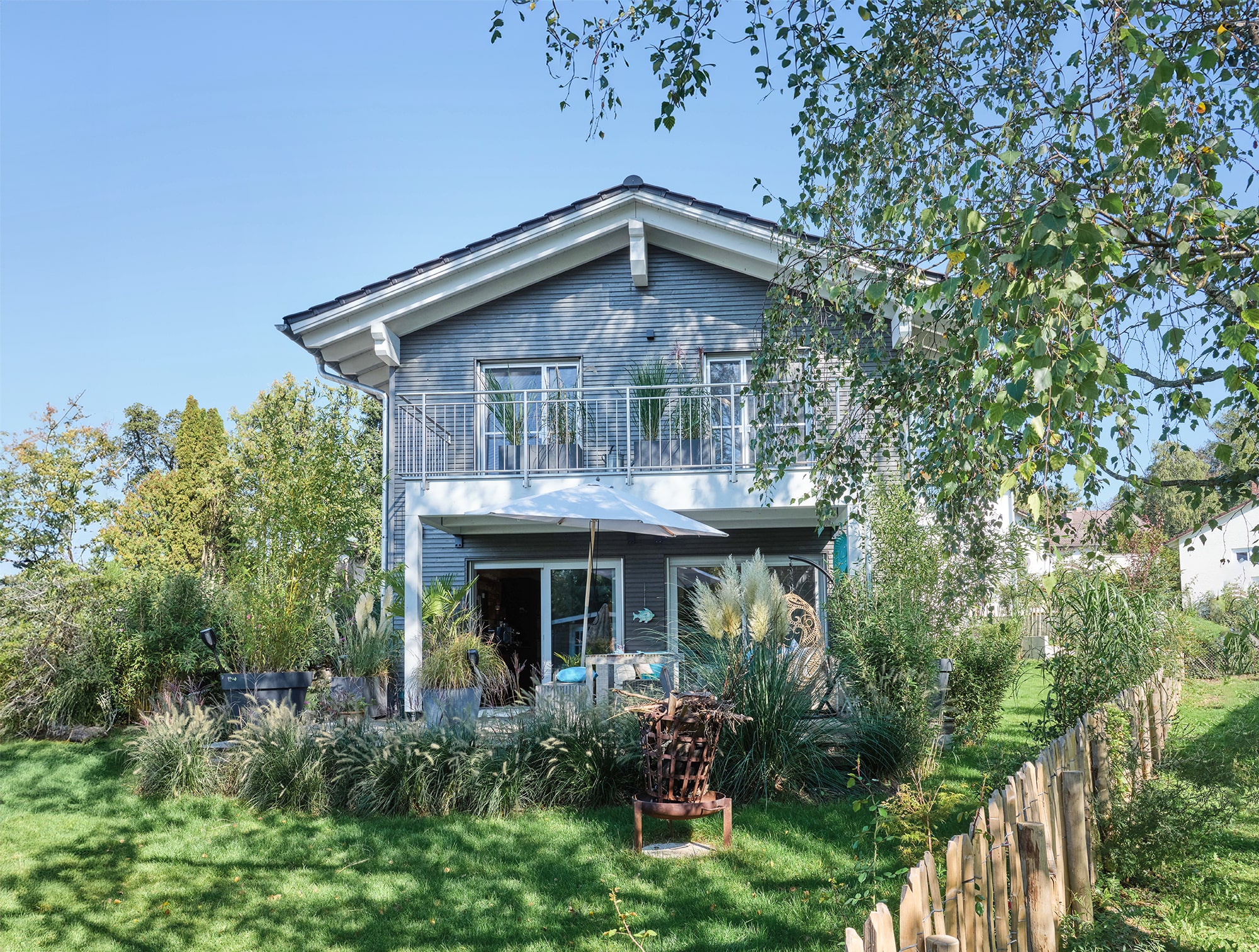 Modernes Schwedenhaus schwarz mit weißen Fenstern und wunderschön angelegtem Garten