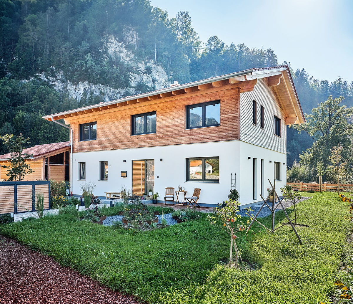 Natürliches Holzhaus mit Kombifassade aus Lärche und Putz mit schönem Vorgarten
