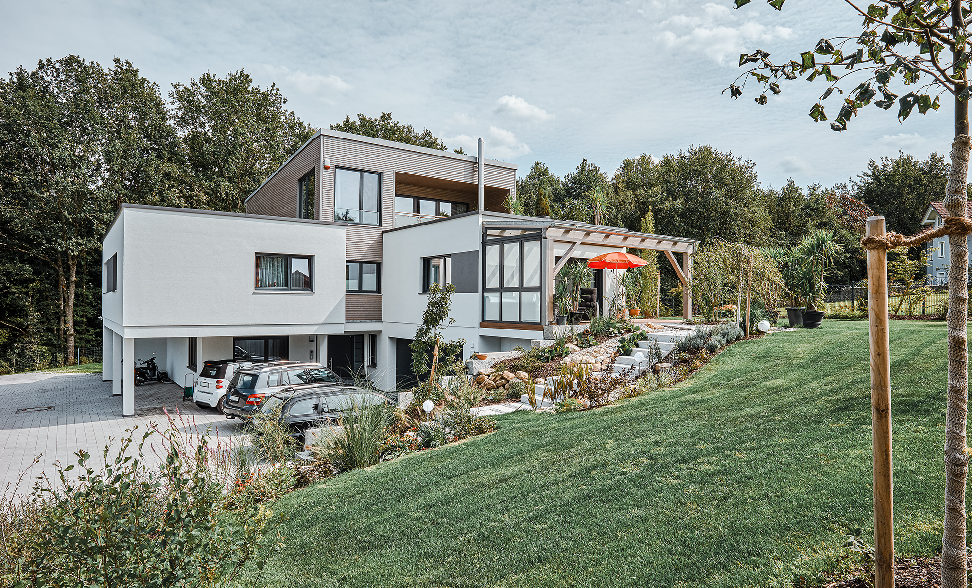 modernes Designhaus im Kubusstil mit überdachter Holzterrasse
